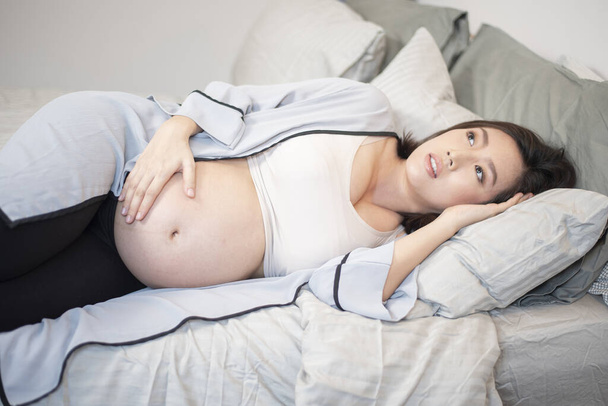 Beautiful asian pregnant woman is sleeping on bed - 写真・画像