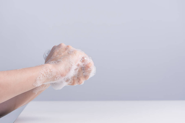 Washing hands. Asian young woman using liquid soap to wash hands, concept of hygiene to protective pandemic coronavirus isolated on gray white background, close up. - 写真・画像