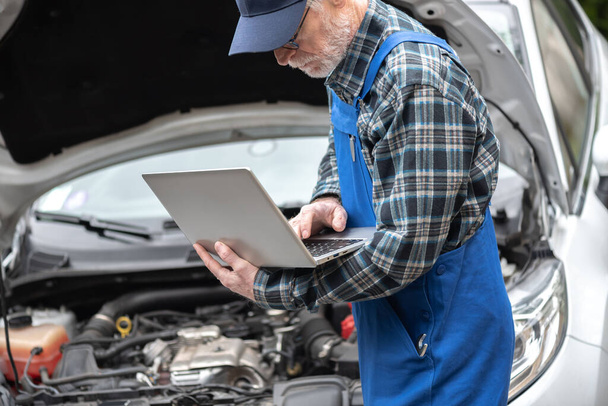 Automechaniker mit Laptop zur Überprüfung des Motors - Foto, Bild