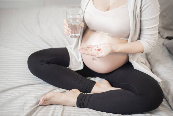 Close up pregnant woman eating vitamin pills  - Foto, imagen