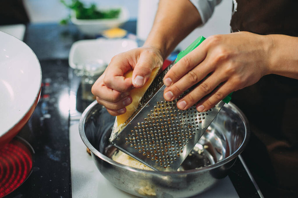 Chef grating cheese, chef hand grating parmesan cheese with grater, Chef rubbing cheese on a grater, close up - 写真・画像