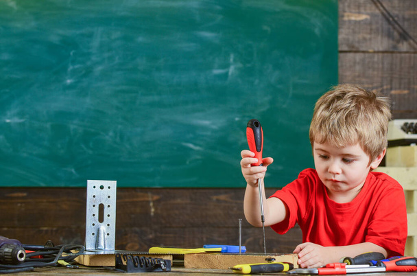 Kid binding screw to board. Cute boy using screwdriver. Educational game concept - Фото, зображення