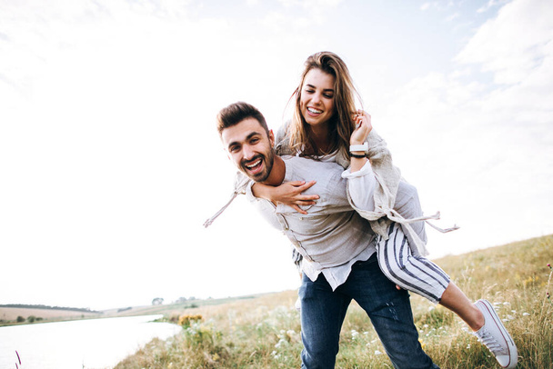 Beautiful loving couple having fun, cuddling, smiling on sky background in field. The guy and the girl hipster travel - Fotografie, Obrázek