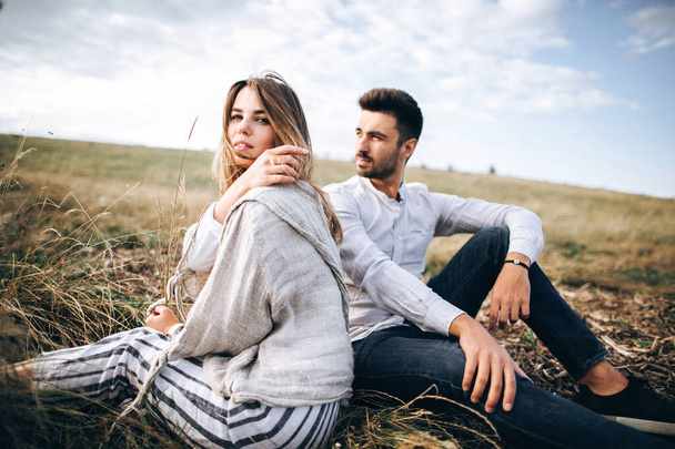 Gyönyörű szerető pár ül a fűben. A srác és a lány hipszter utaznak - Fotó, kép