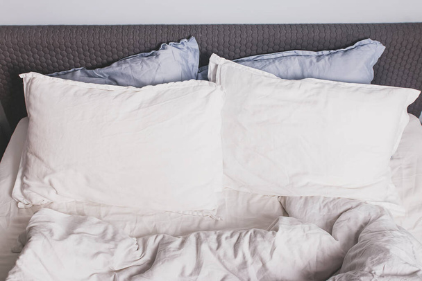 Messy bed with two pillows close-up, - 写真・画像