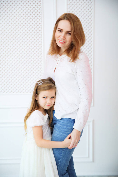 mom and daughter in white in front of white wall. - Fotoğraf, Görsel