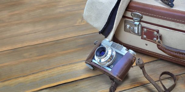 Retro walizka i aparat fotograficzny na drewnianym tle z kapeluszem  - Zdjęcie, obraz