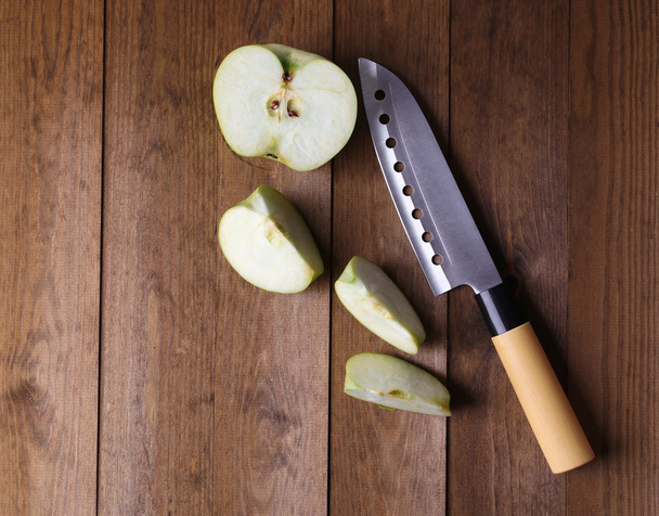 Kitchen knife and green apple, on wooden background - Foto, immagini