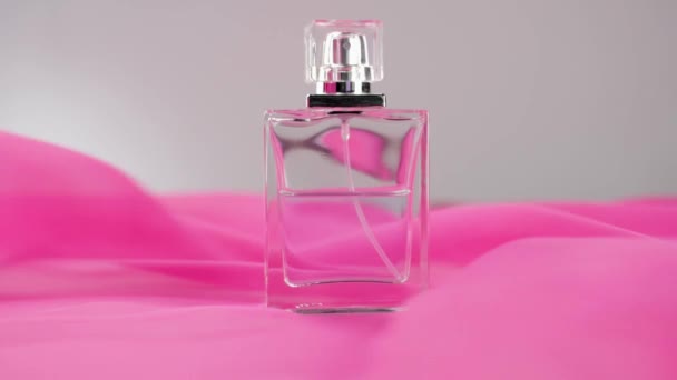Flat surfaced perfume bottle with cyan perfumes or essential oils on the white table. Pink fabric flutters around and waves in the air around the perfume bottle. Concept of aroma and smell. Close up - Footage, Video