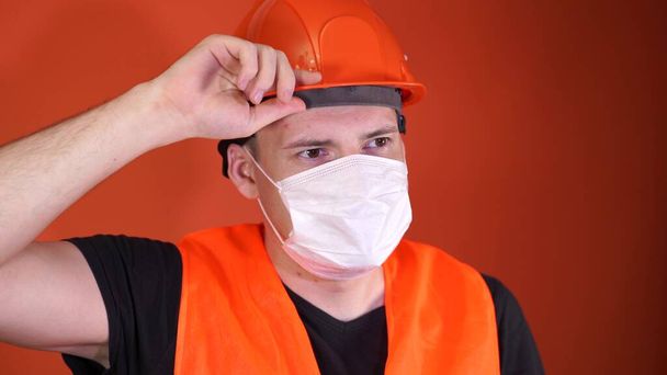 Portrait of young man in medical mask on his face on orange background. Adult male covered face with mask to protect yourself from diseases. Concept of coronavirus epidemic or diseases. - Zdjęcie, obraz