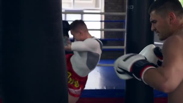 Two Professional Boxers Fiercely Punches and Kicks Punching Bags Near Boxing ring at Gym. Muay Thai Mixed Martial Arts Fighters Practicing Workout. 2x Slow motion 1/2 speed 60 fps 4K - Filmagem, Vídeo