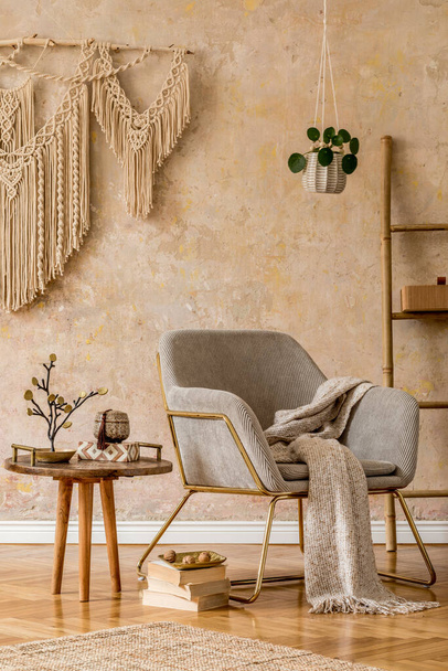 Stylish oriental living room with design armchair, beautiful macrame, wooden ladder, plant, decoration, carpet, coffee table, book and elegant personal accessories in wabi sabi concept. - Foto, Imagen