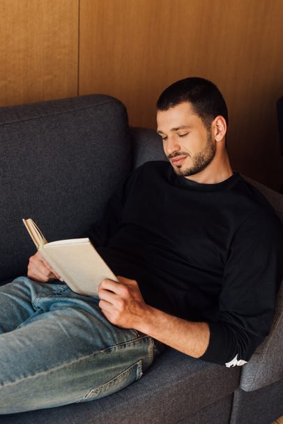 hombre barbudo y guapo leyendo libro en sala de estar
  - Foto, Imagen