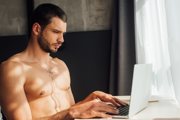 bearded and shirtless freelancer using laptop at home  - Photo, image