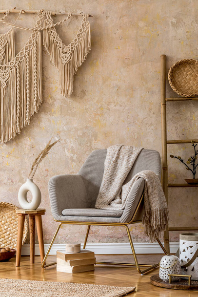Stylish oriental living room with design armchair, beautiful macrame, wooden ladder, plant, decoration, carpet, coffee table, book and elegant personal accessories in wabi sabi concept. - Fotó, kép