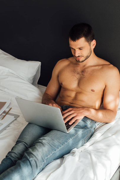 handsome and shirtless freelancer using laptop in bedroom  - Photo, Image