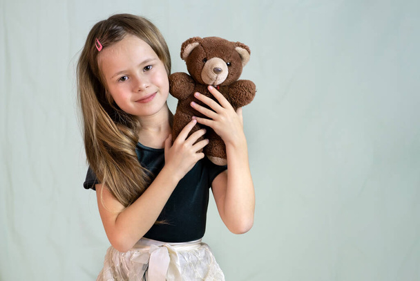 Гарненька дівчинка грає зі своєю плюшевою іграшкою ведмедя
. - Фото, зображення