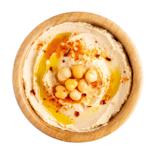 Hummus de grão de bico clássico com azeite e páprica em tigela de madeira isolada em branco. Vista superior
. - Foto, Imagem