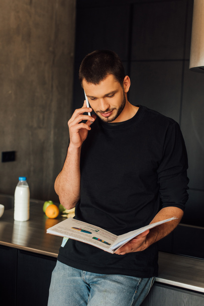 handsome man talking on smartphone while holding charts and graphs  - Фото, зображення