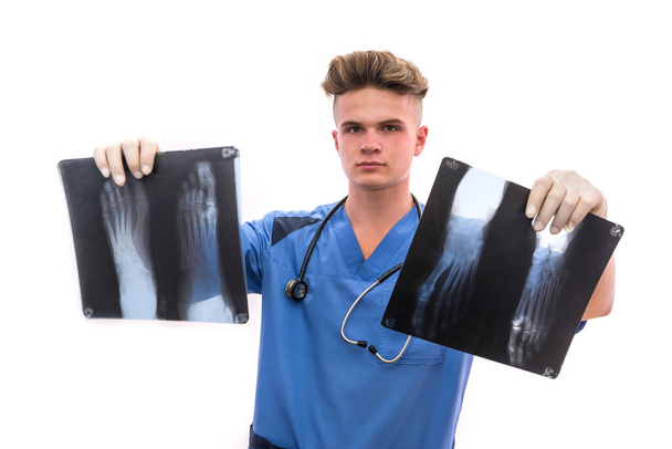 Knappe en jonge dokter met voet röntgenfoto van een patiënt. Medisch hulpconcept - Foto, afbeelding