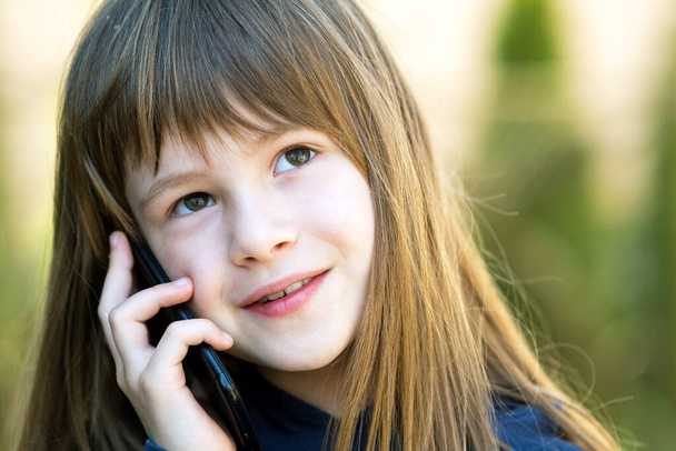 Portrait of pretty child girl with long hair talking on cell phone. Little female kid communicating using smartphone. Children communication concept. - Fotó, kép