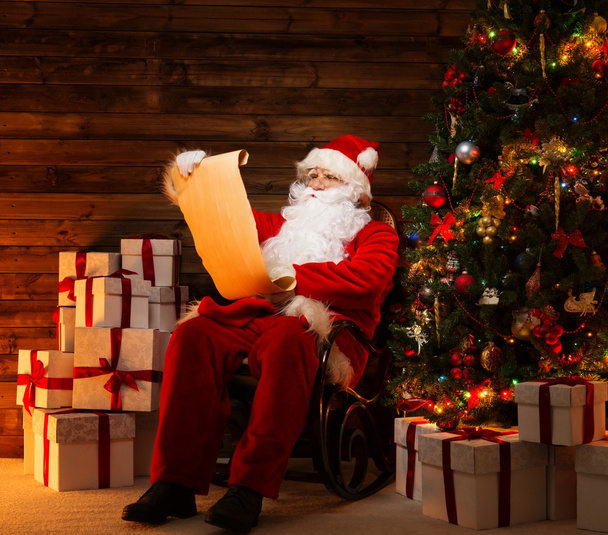 Άγιος Βασίλης στο ξύλινο σπίτι εσωτερικό ανάγνωση κυλίνδρων λίστα επιθυμιών - Φωτογραφία, εικόνα