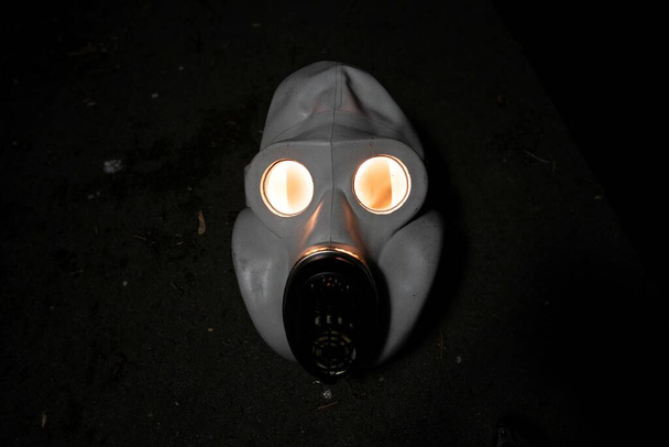Ancien masque à gaz militaire soviétique dans l'obscurité avec une lumière chaude à l'intérieur
. - Photo, image