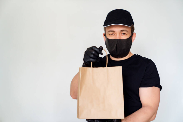 Delivery man in black hold cardboard bag - Fotoğraf, Görsel