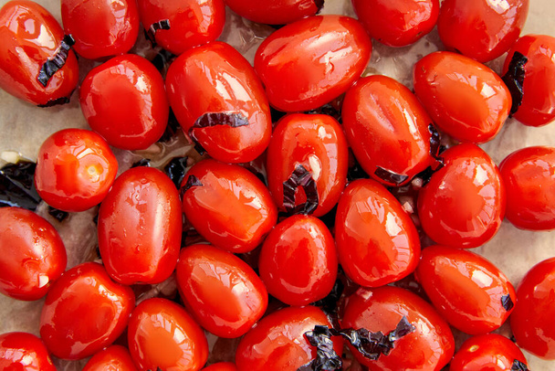Top näkymä tomaatit leikattu basilika lehdet leivinpaperilla
  - Valokuva, kuva