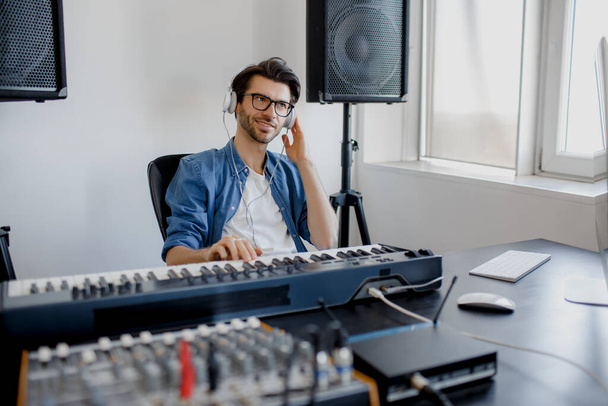 Male music arranger composing song on midi piano and audio equipment in digital recording studio. Man produce electronic soundtrack or track in project at home. - Foto, Bild