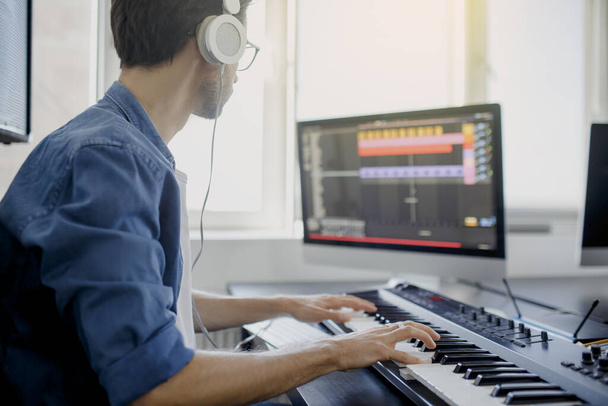 skladatel drží klavírní klávesy v nahrávacím studiu. technologie výroby hudby, člověk pracuje na klavíru a počítačové klávesnici na stole. - Fotografie, Obrázek