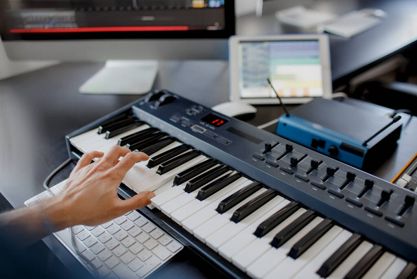 skladatel drží klavírní klávesy v nahrávacím studiu. hudební technologie, člověk pracuje na klavíru a počítačové klávesnici na stole. koncept close up. - Fotografie, Obrázek