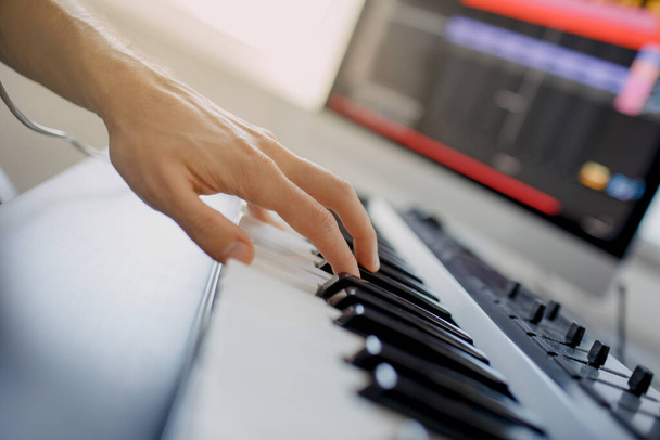 композитор руки на клавішах фортепіано в студії звукозапису. технологія виробництва музики, людина працює на піаніно та комп'ютерній клавіатурі на столі. крупним планом концепція
. - Фото, зображення