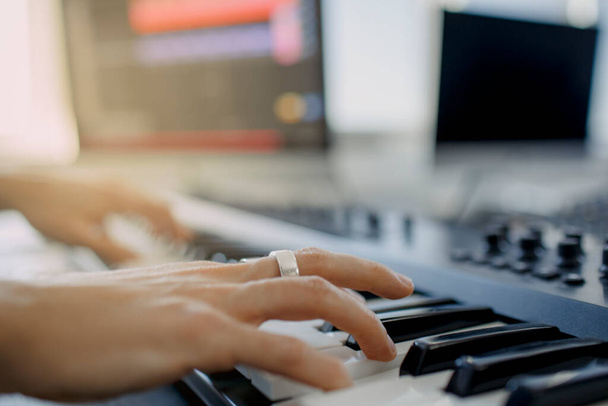 Kayıt stüdyosunda besteci elleri piyano tuşlarına basıyor. Müzik prodüksiyon teknolojisi, adam piyano ve bilgisayar klavyesi üzerinde çalışıyor. konsepti kapat. - Fotoğraf, Görsel