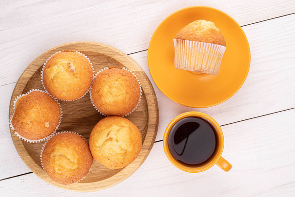 Gruppo di sei piccoli muffin al forno con caffè su legno bianco
 - Foto, immagini