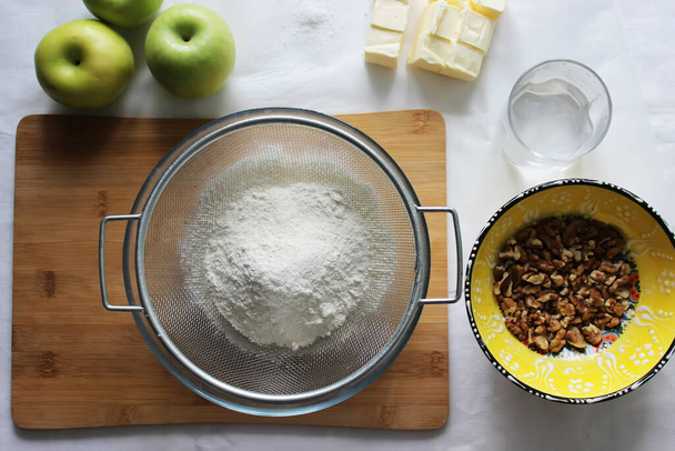 Preparations for Apple pie: flour, apples, butter, nuts. Homemade cake. Housework. - Photo, image