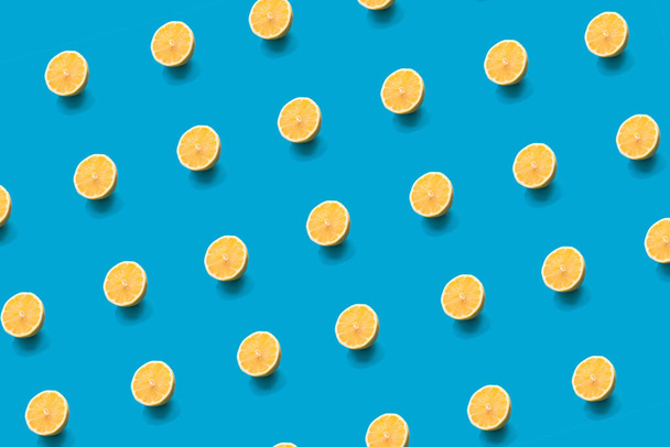 Pattern lemon fresh yellow half slice close up on bright blue color background. Trendy summer minimal concept. Flat lay. Selective soft focus. - Foto, imagen