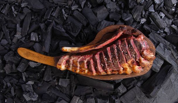 grilled tomahawk steak on wooden plate ready for eat. On background coal - Photo, Image