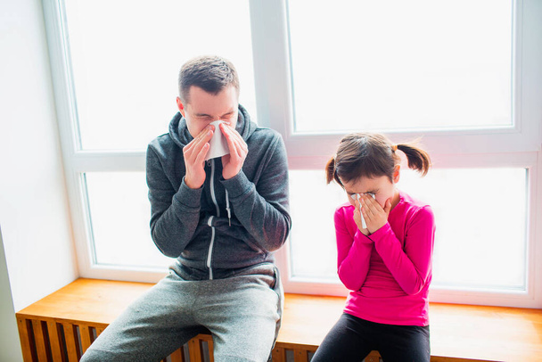 young father and his cute little daughter have handkerchief and runny nose after training on a mat indoor. ute kid and daddy have exercises near the window in her room. - Photo, Image