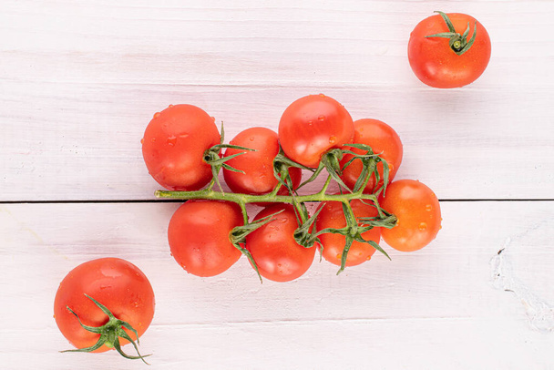 Lot of whole fresh red cherry tomato on white wood - Foto, afbeelding