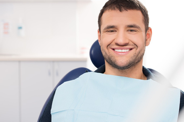 χαμογελαστός νεαρός άνδρας σε χειρουργική επέμβαση του οδοντιάτρου - Φωτογραφία, εικόνα