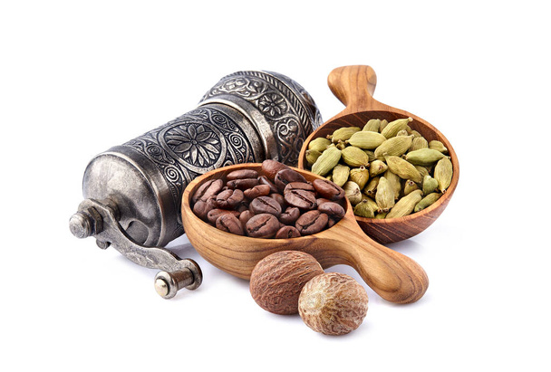Coffee beans in a wooden spoon with  cardamom and nutmeg on white background. - Photo, Image