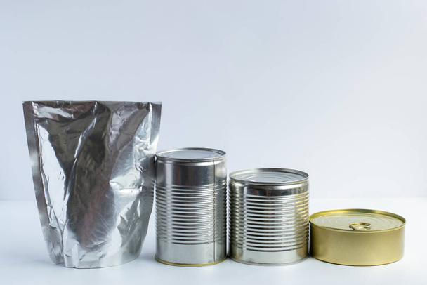 Metal cans of different sizes, metallized flexible packet on a white background. A variety of packaging for canned food. Space for text. Copy space - Valokuva, kuva