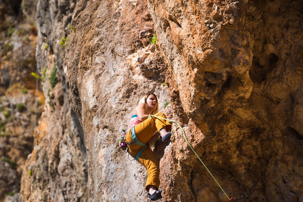 Egy lány sziklát mászik. A sportoló a természetben edz. A nő legyőzi a nehéz hegymászási útvonalat. Erős mászó. Extrém hobbi. Sziklamászás Törökországban. - Fotó, kép