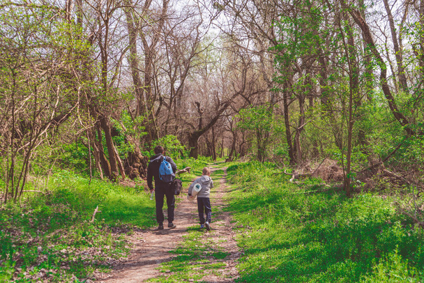 Gezginler - genç yürüyüşçü ve babası bahar ormanlarında, patikadan aşağıya doğru ilerliyorlar. - Fotoğraf, Görsel