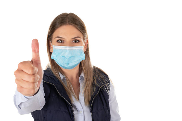 Caucasian woman with surgical mask showing thumbs up on isolated background - Foto, Bild