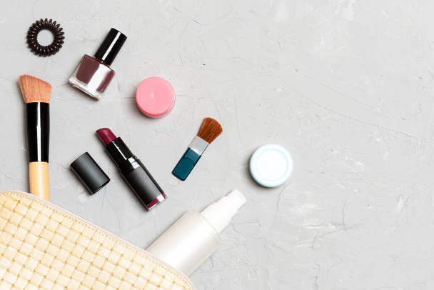 Blick von oben auf Make-up-Produkte, die aus einer Kosmetiktasche auf Zementgrund gefallen sind. Kosmetisches Konzept mit Raum für Ihre Gestaltung. - Foto, Bild