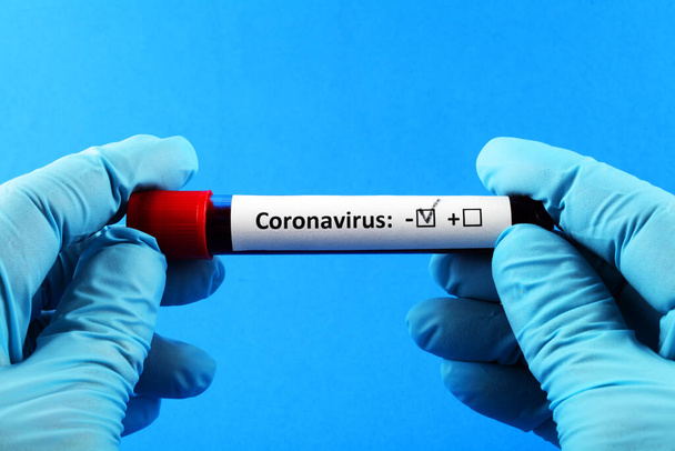 Coronavirus. La main du docteur dans un gant bleu. Échantillon de sang in vitro pour analyse. Fond bleu
. - Photo, image