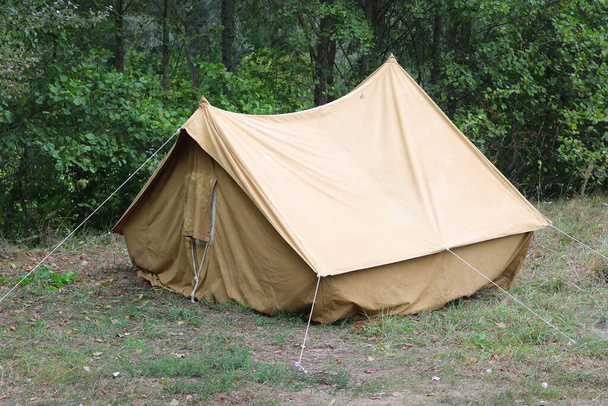 Старый холст палатки в туристическом лагере летом на фоне зеленых деревьев
 - Фото, изображение