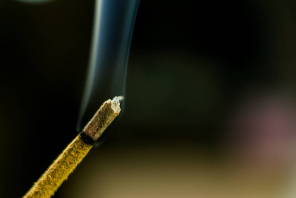 A smoking aromatic stick on a dark blurred  background. - Фото, изображение